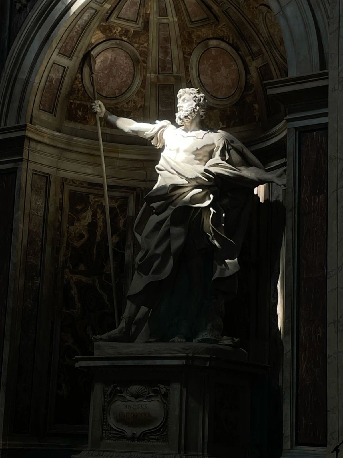 Estátua clássica segurando um bastão, iluminada em um nicho